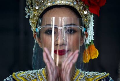 Una bailarina, con protector facial, actúa en un templo en Bangkok (Tailandia). El país está reforzando la seguridad a lo largo de la frontera con Myanmar a causa de varios focos de coronavirus.