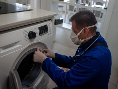 Un técnico repara una lavadora durante el confinamiento.