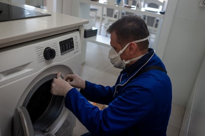 Un técnico repara una lavadora durante el confinamiento.