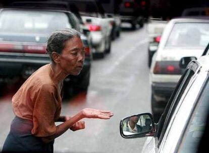 Una anciana birmana pide limosna a un conductor en las calles de Yangon.