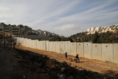 Dos niños ruedan neumáticos mientras corren a lo largo de la barrera israelí en el campamento de refugiados de Shuafat, en el este de Jerusalén.
