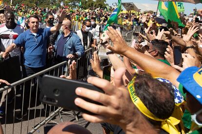 O presidente Jair Bolsonaro acena a apoiadores, aglomerados em plena pandemia de covid-19, em março.