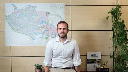 Alberto Escribano, alcalde de Arganda del Rey, junto a un mapa de la localidad, situado en su despacho del Ayuntamiento; en el mapa, la zona rosa son las viviendas y la gris, el polígono industrial.