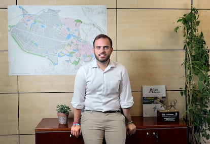 Alberto Escribano, alcalde de Arganda del Rey, junto a un mapa de la localidad, situado en su despacho del Ayuntamiento; en el mapa, la zona rosa son las viviendas y la gris, el polígono industrial.