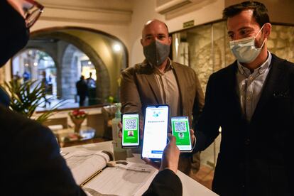 Dos comensales muestran el código QR de certificación de test negativo o vacunación para acceder al Restaurante Cal Ros de Girona.