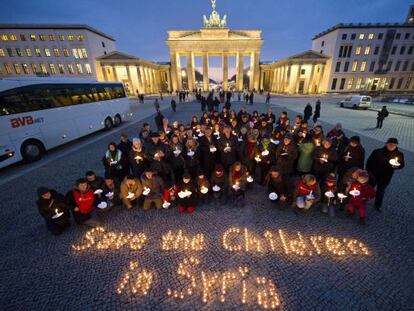Un grupo de personas forma, con velas, la frase "Salvad a los niños de Siria", ayer en la puerta de Brandenburgo en Berlín.