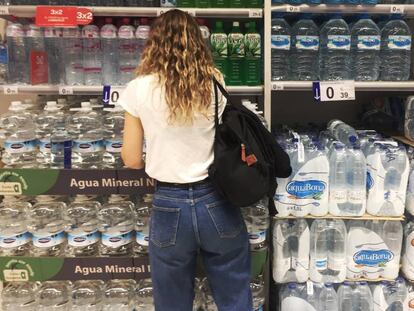 Una joven frente al estante de botellas de agua de plástico en un supermercado en Madrid.