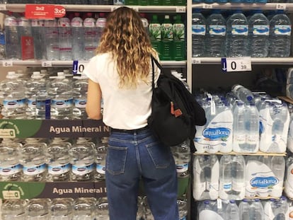 Una joven frente al estante de botellas de agua de plástico en un supermercado en Madrid.