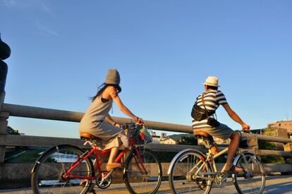 Una pareja cruza en bici uno de los puentes que atraviesan el río Kamo, en Kioto.