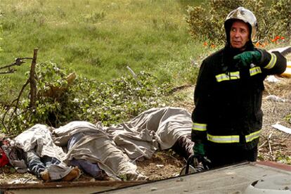 Un bombero, junto a tres de los cadáveres en el lugar del accidente en el que murieron siete personas en la autovía A-1.