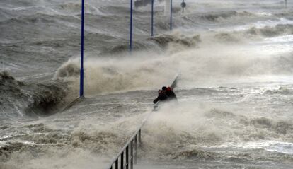 El temporal en la costa, hace que dos hombres se tengan que sujetar a la valla del muelle del ferry en Dagebuell, Alemania. El paso del ciclón "Xaver" provocará rachas de viento de más de 100 kilómetros por hora.