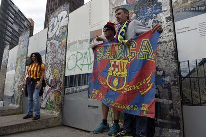 Varios aficionados del Barça ante restos del muro de Berlín