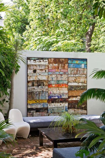 Exterior. La presencia de una gran pared blanca rompe en el patio con el viejo estilo. La obra de Aquiles trae los colores de la isla; la naturaleza frondosa, el aire tropical.