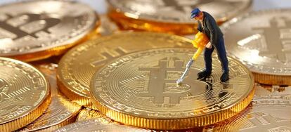 Una figura en miniatura sobre una pila de monedas que represetan bitcoins.