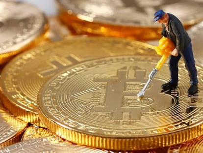 Una figura en miniatura sobre una pila de monedas que represetan bitcoins.