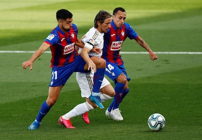 El jugador del Real Madrid Luka Modric (C) disputa el balón entre los jugadores del Eibar Alvaro Tejero y Fabian Orellana, durante el partido que han disputado los dos equipos en el estadio Alfredo Di Stefano.