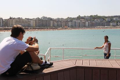 Una pareja de turistas se fotografía en la playa de La Concha de San Sebastián.