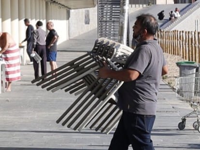 Workers at a beach restaurant in Barcelona putting away tables and chairs after regional authorities decided to shut down food and drink establishments.