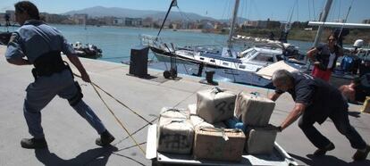 Dos funcionarios transportan fardos de droga incautada en 2010 en un velero de Algeciras.