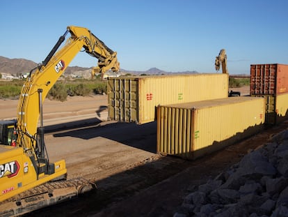 A construction crew removes shipping containers along the border between US and Mexico.