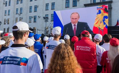 Un grupo de personas sigue un discurso del presidente ruso, Vladímir Putin, en Lugansk (Ucrania).