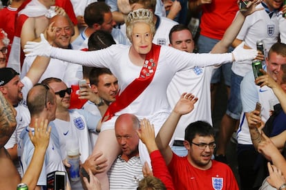 Un seguidor de la selección de Inglaterra con una máscara de la reina Isabel II es llevado en hombros por sus compañeros antes del partido frente a Eslovaquia en la Eurocopa, en Saint-Étiennne, Francia.