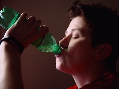 Un adolescente bebe de una botella.