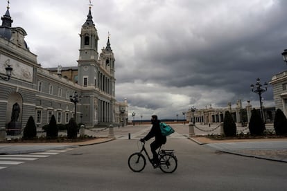 Un repartidor monta en bici al lado de la plaza que separa La Almudena del Palacio Real. Un lugar siempre concurrido por turistas. Imagen tomada el 16 de marzo.