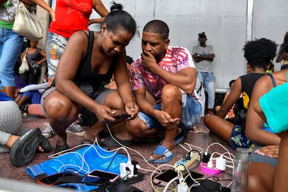 Afectados por el huracán cargan batería a sus teléfonos móviles después de los daños generados en la red eléctrica del país. 