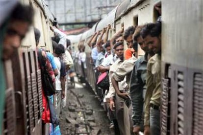 Pasajeros a bordo de dos trenes de cercanías en plena hora punta, ayer en Bombay.