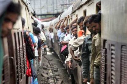 Pasajeros a bordo de dos trenes de cercanías en plena hora punta, ayer en Bombay.