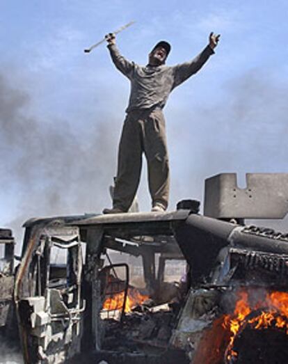 Un iraquí celebra un ataque sobre un vehículo en llamas en Bagdad.