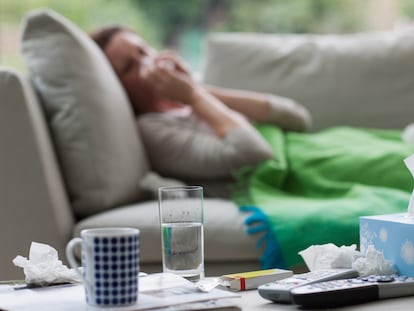 Sick woman laying on sofa blowing nose