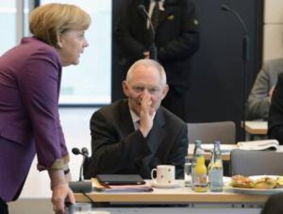 La canciller alemana, Angela Merkel (izda), y el ministro de Finanzas, Wolfgang Schaeuble, (dcha) conversan antes de la sesión especial de la Unión Democristiana (CDU) hoy en Berlín (Alemania).