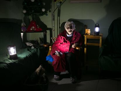 Rosa, de 73 años, iluminada con linternas en el salón de su casa.