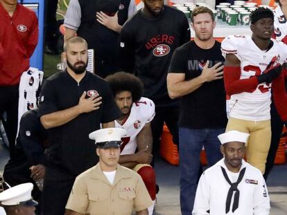 Colin Kaepernick espera sentado mientras suena el himno estadounidense antes de un partido de pretemporada de los San Francisco 49ers.