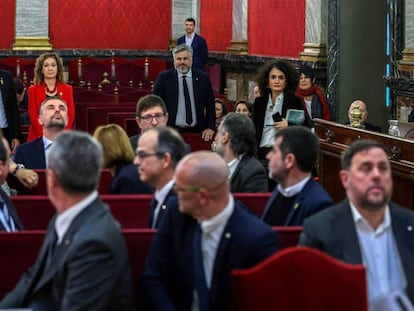 Catalan premier Quim Torra waves at the defendants inside the Supreme Court.