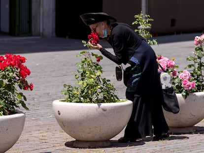Una mujer se baja la mascarilla para oler unas rosas en Roma, el pasado mayo, en pleno confinamiento.