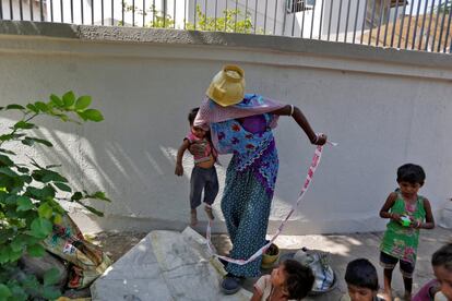 Sarta Kalara, a construction worker, holds her 15-month-old Shivani as a barrier tape is tied to Shivani's ankle to prevent her from running away when Kalara works nearby in Ahmedabad, India, April 20, 2016. Kalara says she has no option but to tether her daughter Shivani to a stone despite her crying, while she and her husband work for 250 rupees ($3.8) each a shift digging holes for electricity cables in the city of Ahmedabad. There are about 40 million construction workers in India, at least one in five of them women, and the majority poor migrants who shift from site to site, building infrastructure for India's booming cities. Across the country it is not uncommon to see young children rolling in the sand and mud as their parents carry bricks or dig for new roads or luxury houses. REUTERS/Amit Dave       SEARCH "TIED TODDLER" FOR THIS STORY. SEARCH "THE WIDER IMAGE" FOR ALL STORIES