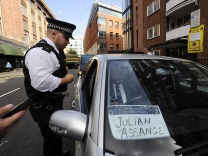 Un policía pide a un chófer que aparentemente iba a recoger a Assange frente a la embajada de Ecuador que abandone la zona.