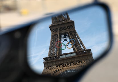 La torre Eiffel, con los aros olímpicos, en el reflejo de un espejo retrovisor.