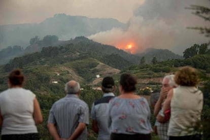 Residents observe smoke billowing from a forest fire raging near Montana Alta on the island of Gran Canaria.