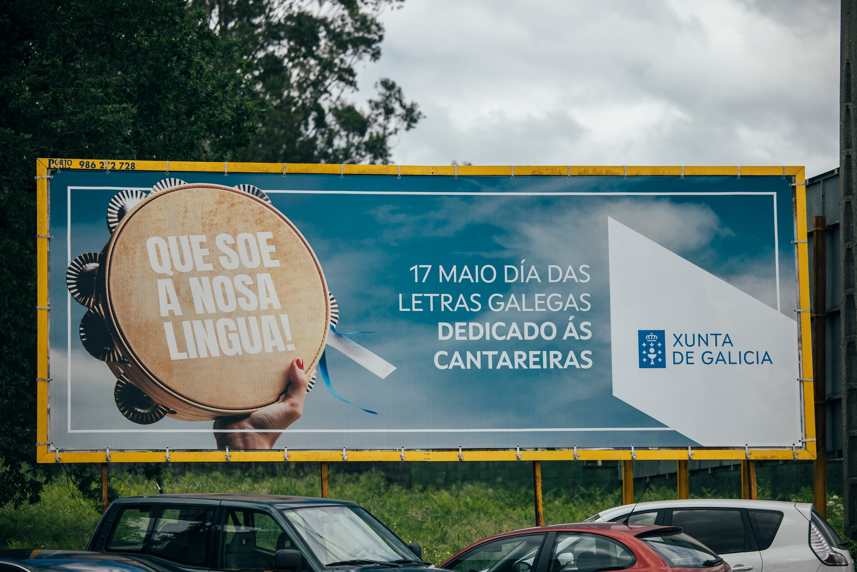 Valla publicitaria, en el municipio coruñés de Teo, de la Xunta por el Día das Letras Galegas, 17 de mayo, dedicado a las 'cantareiras', tradición oral de las cantadoras que se acompañan con una pandereta.