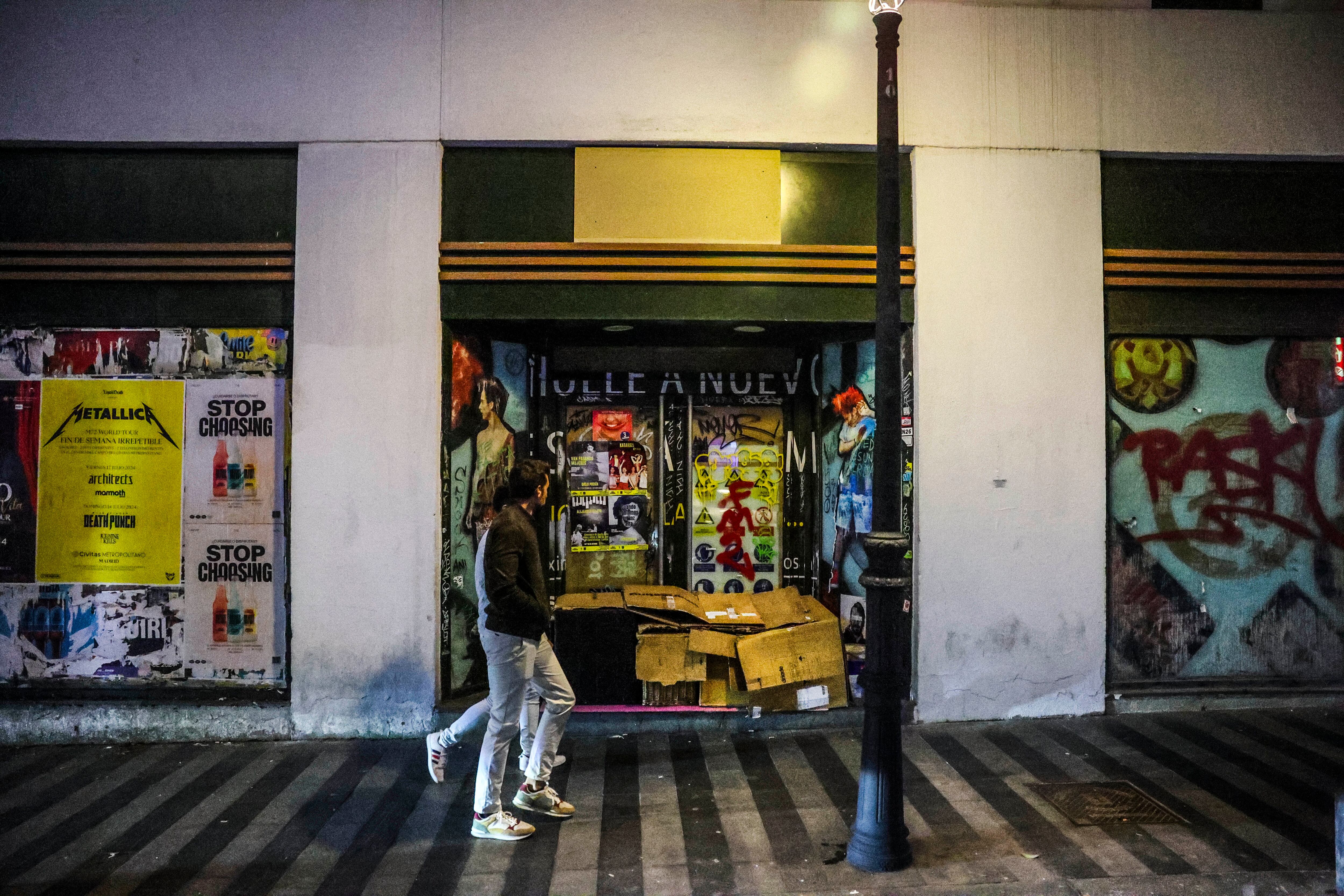 Una pareja pasa este sábado delante de una persona sin hogar que duerme en los aledaños a Gran Vía. 