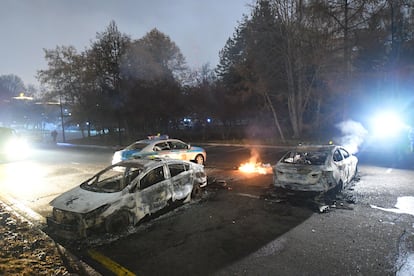 Varios coches de policía tras se quemados durante las protestas en Almaty, este miércoles.