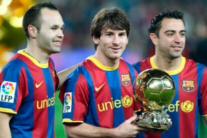 Xavi, Messi e Iniesta ofrecen el Balón de Oro al público del Camp Nou.