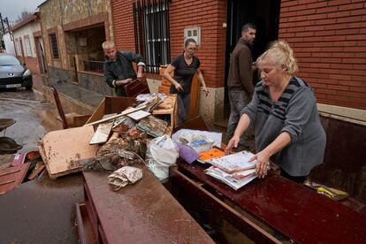 Una familia afectada por las inundaciones en Roca de la Sierra (Badajoz) saca objetos de su vivienda para evitar que se estropeen 
