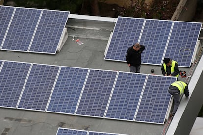 Operarios instalan paneles solares en una cubierta de un edificio.