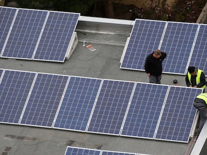 Operarios instalan paneles solares en una cubierta de un edificio.