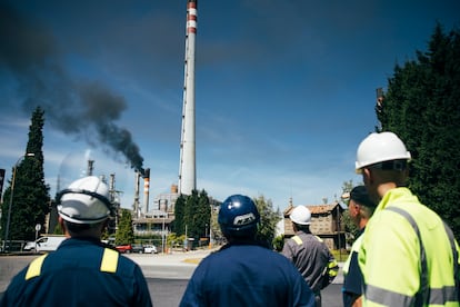 Trabajadores de la refinería de Repsol en A Coruña, a la entrada de la factoría donde se activó un proceso de seguridad que crea una columna de humo en las chimeneas, visible desde toda la ciudad.